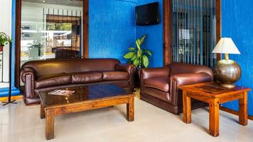 A living room with a brown leather sofa, a wooden coffee table, and a small wooden side table with a lamp.