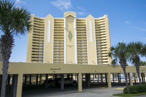 Stunning hotel with a symmetrical facade and flat roof, surrounded by a covered parking area and lush palm trees.
