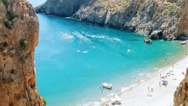 Una playa costera con acantilados rocosos y agua turquesa cristalina.