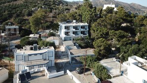 Zona residencial con edificios modernos, incluyendo una casa de varios pisos con balcones, rodeada de árboles y colinas.