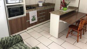 Une cuisine compacte équipée d’un four à micro-ondes, d’un four et d’un évier. Un petit coin repas avec une table et des chaises est également disponible.
