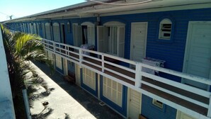 Un bâtiment à la façade bleue, aux portes blanches et doté d’un balcon avec une balustrade blanche.