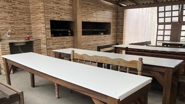 Un coin repas rustique avec des tables et des bancs en bois, des murs en briques et un barbecue intégré.