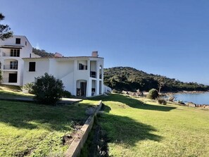A white two-story house with a balcony, a grassy yard, and a view of the sea. - Apartment by the sea for 4 (CALCATOGGIO)