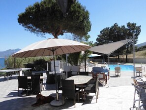 An outdoor seating area with tables and chairs, umbrellas, and a pool. - Apartment by the sea for 4 (CALCATOGGIO)