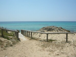 Una platja sorrenca amb un camí de fusta que condueix a la mar.