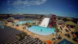 A water park with multiple pools, a large water slide, and sun loungers.
