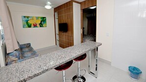 A kitchen with a granite countertop, wooden cabinets, and a painting of a flower.