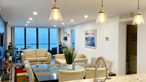 A modern kitchen with a central island, a dining area with a sofa and chairs, and a view of the outdoors.