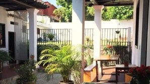 A covered patio area with a glass table, potted plants, and a view of the surrounding neighborhood. - Casa LOBE (Ocosingo)