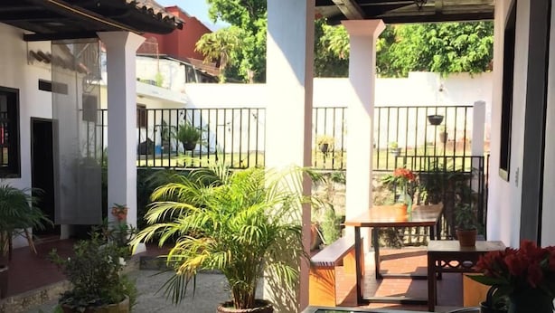 A covered patio area with a glass table, potted plants, and a view of the surrounding neighborhood. - Casa LOBE (Ocosingo)
