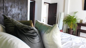 A bedroom with a bed, dark wooden door, and a potted plant. - Casa LOBE (Ocosingo)