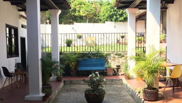 A courtyard with a central water feature, surrounded by potted plants and a blue bench. - Casa LOBE (Ocosingo)