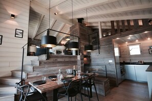 A rustic interior with a wooden staircase, a dining area with a wooden table and chairs, and a kitchen with modern appliances. - Chalet D'en Haut Hameau Granges (Bolquère)