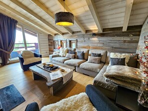 A cozy living room with a wooden ceiling, a sofa set, a coffee table, and a fireplace.