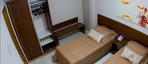 A room with two beds, a wooden wardrobe, a bench, and a wall-mounted telephone.