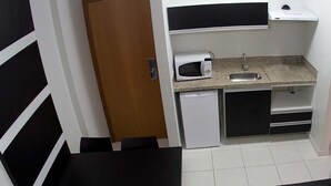 Eine kleine Küche mit Mikrowelle, Spüle und kleinem Kühlschrank.