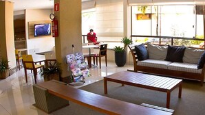 Eine geräumige Lobby mit einer Holzdavonia, einem Couchtisch und einem an der Wand montierten Fernseher.