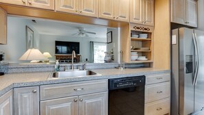 Eine moderne Küche mit Granit-Arbeitsplatten, Edelstahlgeräten und hellen Holzschränken.