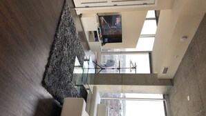 A high-ceiling room with a large window, a flat-screen TV mounted on the wall, and a concrete floor. - The Ultimate Vacation Spot! Modern at the same time! (Houston)