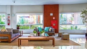 A spacious lobby with a wooden bench, sofas, and potted plants. - Riviera Park Thermas - Oferta Caldas (Caldas Novas)