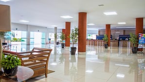 A spacious lobby with a reception desk, large pillars, and potted plants. - Riviera Park Thermas - Oferta Caldas (Caldas Novas)