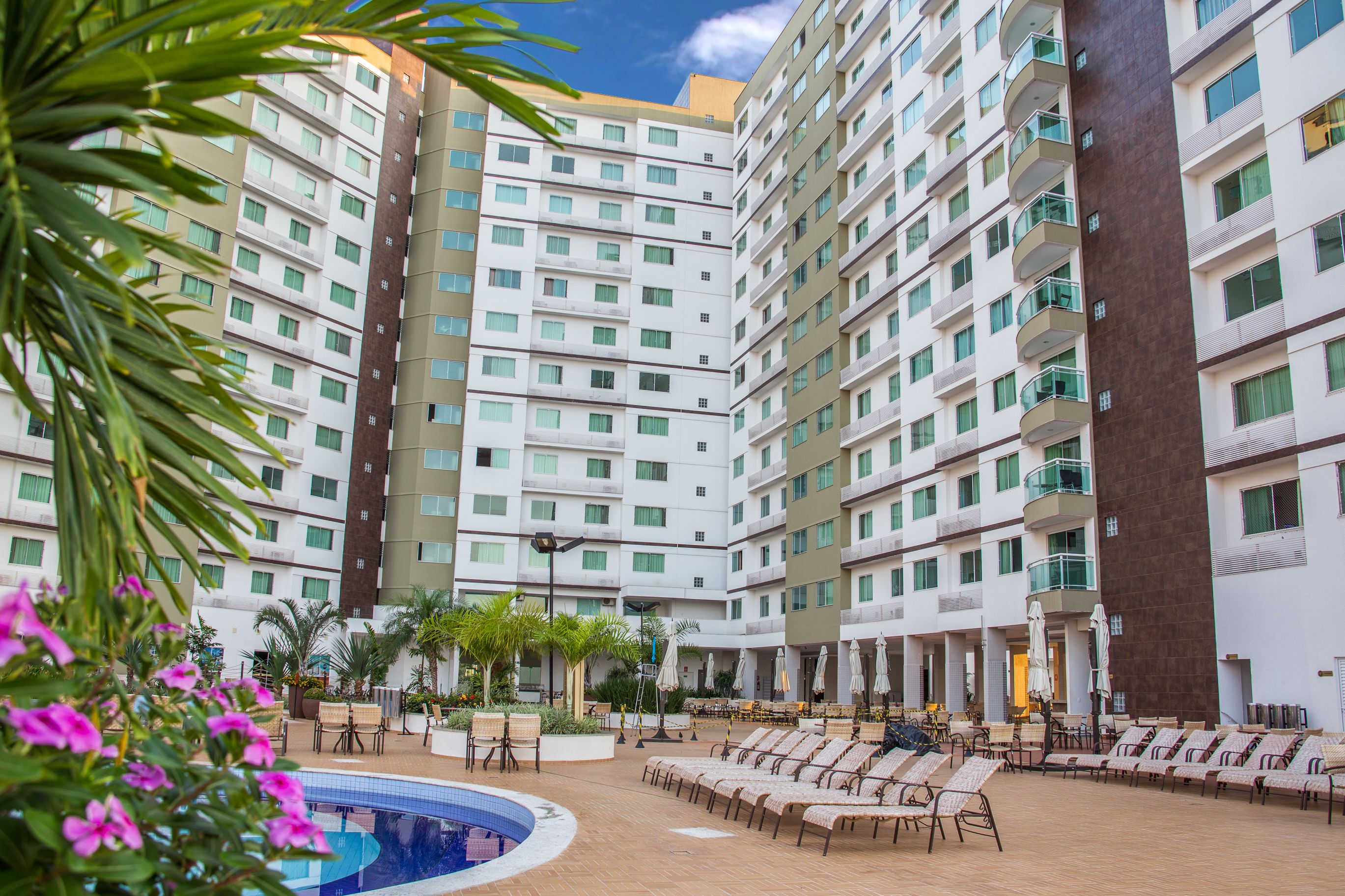 A hotel with multiple floors, outdoor pool, and lounge area with sun loungers.