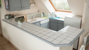 Een kleine keuken met een raam, een spoelbak en een compacte koelkast.