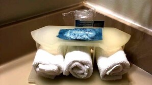 A bathroom sink with a soap dispenser and three rolled towels on a tray. - Cedar Stables Inn and Suites (Sandusky)
