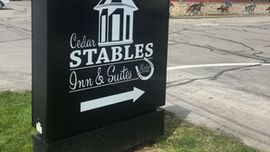 A sign for Cedar Stables Inn & Suites at Boutique Hotel, featuring a directional arrow. - Cedar Stables Inn and Suites (Sandusky)