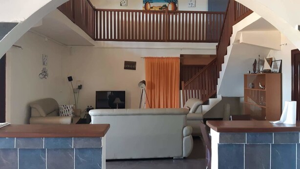 Un salon avec un canapé, un téléviseur et un escalier menant à l’étage supérieur.