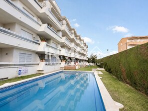 Un immeuble d’appartements moderne doté d’une piscine, de balcons et d’une pelouse bien entretenue.