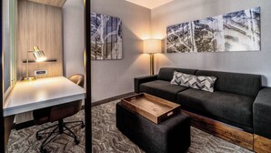 A modern hotel room with a desk, a sofa, and two wall-mounted lamps. - SpringHill Suites by Marriott Oakland Airport (Oakland)