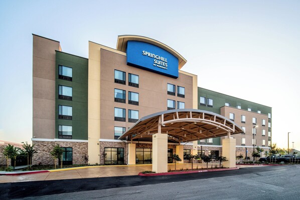 A modern hotel with a prominent signage, a covered entrance, and a parking lot.