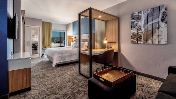 A hotel room with a bed, desk, chair, and a large window. - SpringHill Suites by Marriott Oakland Airport (Oakland)