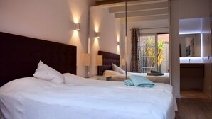 Una camera d'hotel con un letto grande, lampade sui comodini, uno specchio e vista sull'esterno.