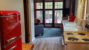Una cocina con un refrigerador Galanz rojo, una estufa blanca y un comedor con un banco y sillas.