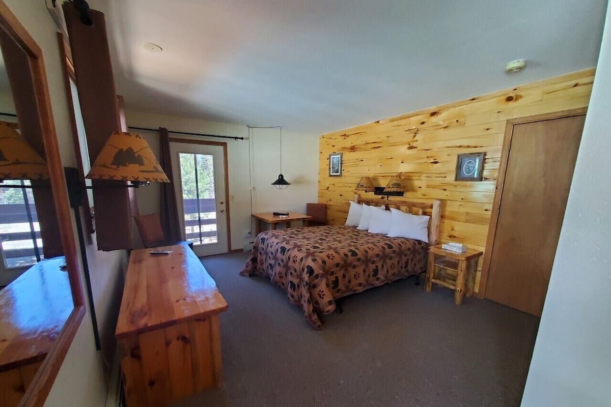 Ein Zimmer mit einem Bett, einem Schreibtisch, einer Lampe und einer Holzwand.