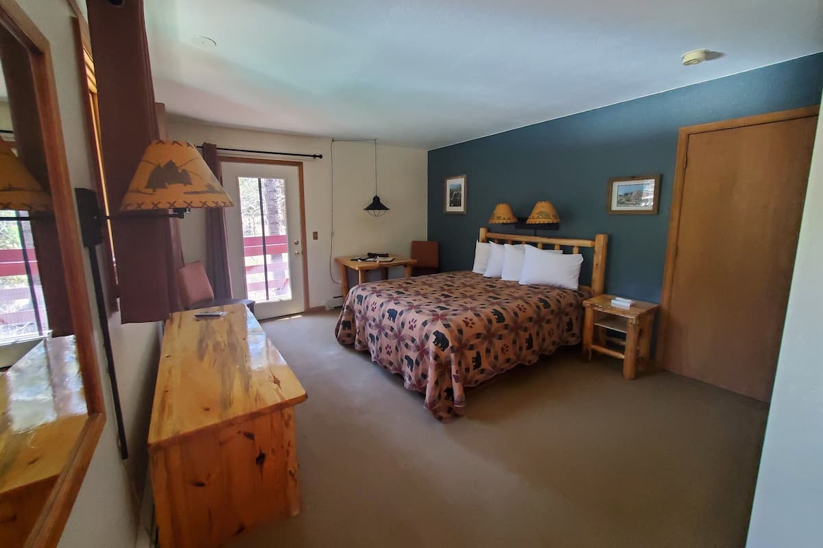 Ein Schlafzimmer mit Bett, einem Holztisch, einem Stuhl, einem Tisch, einer Tür und einem Fenster.