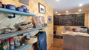Un interior acogedor con paredes de madera, una pizarra con información sobre eventos y estantes con diversos objetos.