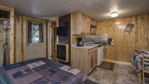 Una habitación compacta con cama, kitchenette y un pequeño comedor.