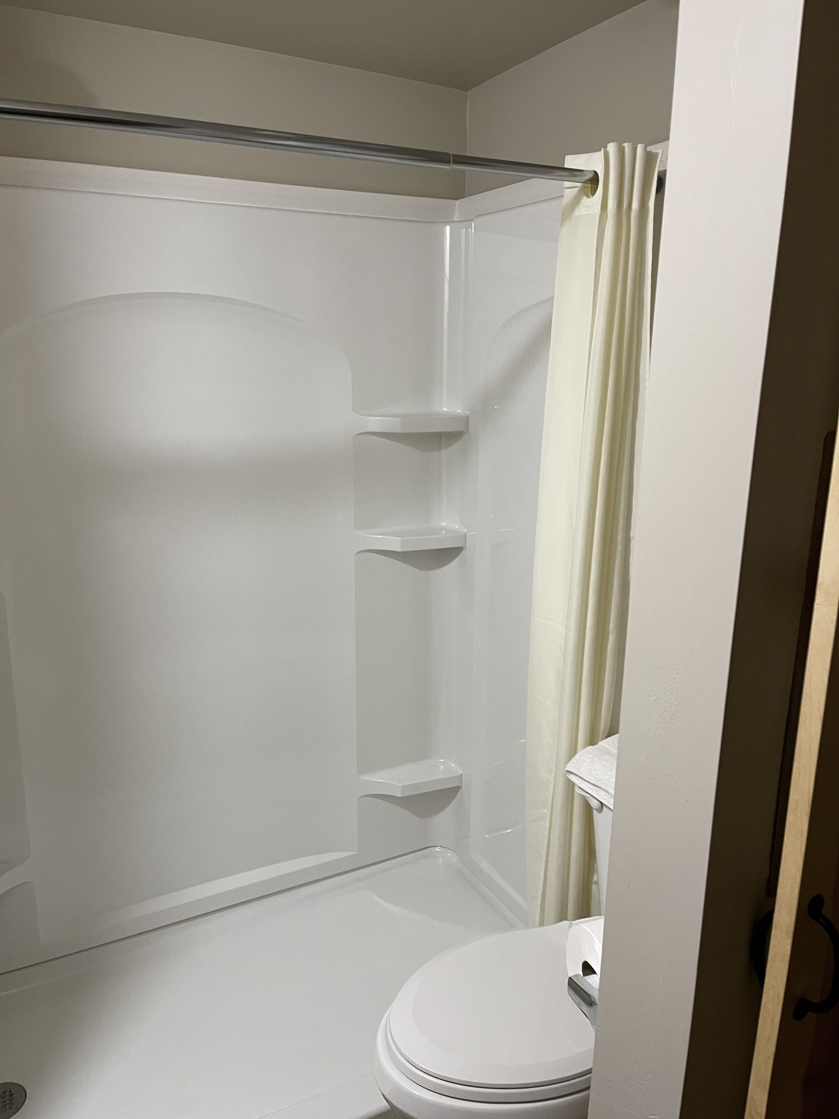 Un baño con ducha, inodoro y toallero.