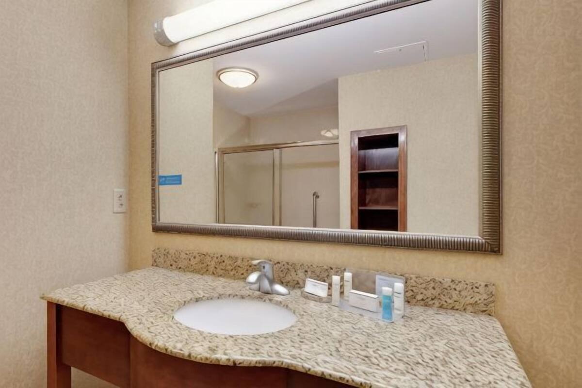 A bathroom with a sink, mirror, and toiletries.