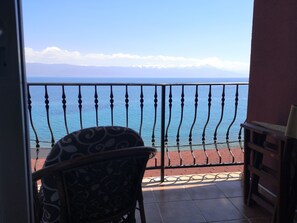 A balcony with a view of the sea and mountains.