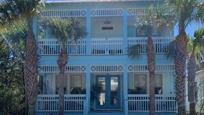 Un bâtiment à deux étages, doté d’une façade bleu clair, de balustrades blanches et d’une entrée centrale avec des marches.