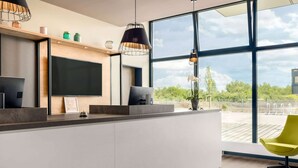 Een moderne keuken met een groot eiland, een flatscreen televisie, hanglampen en uitzicht op het omliggende landschap.