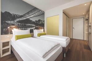 Une chambre d’hôtel avec deux lits, une fresque représentant un pont au-dessus de l’eau et une porte donnant accès à la salle de bain.