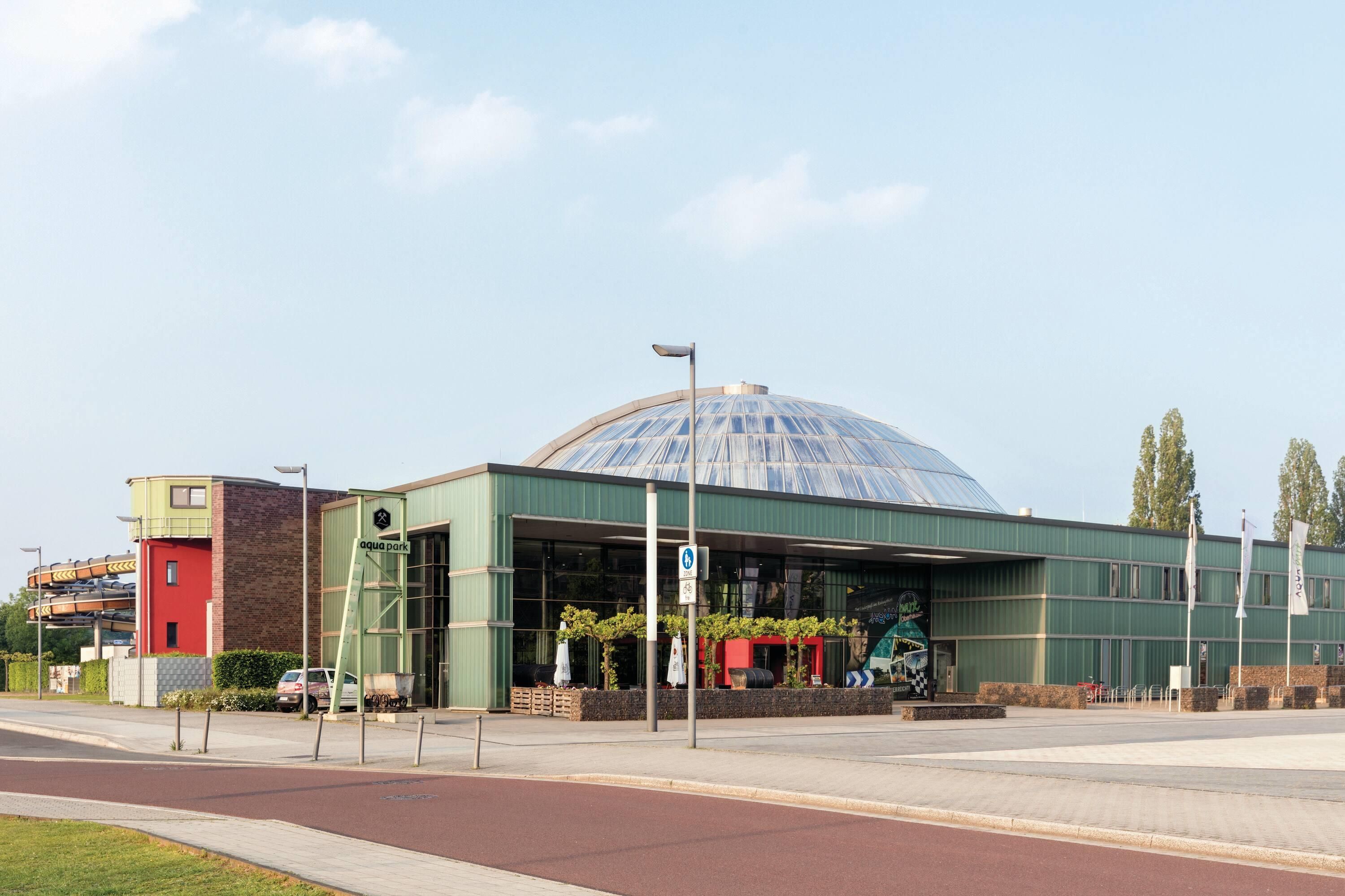 A building with a large glass dome, a green facade, and a sign indicating 'aqua park'.