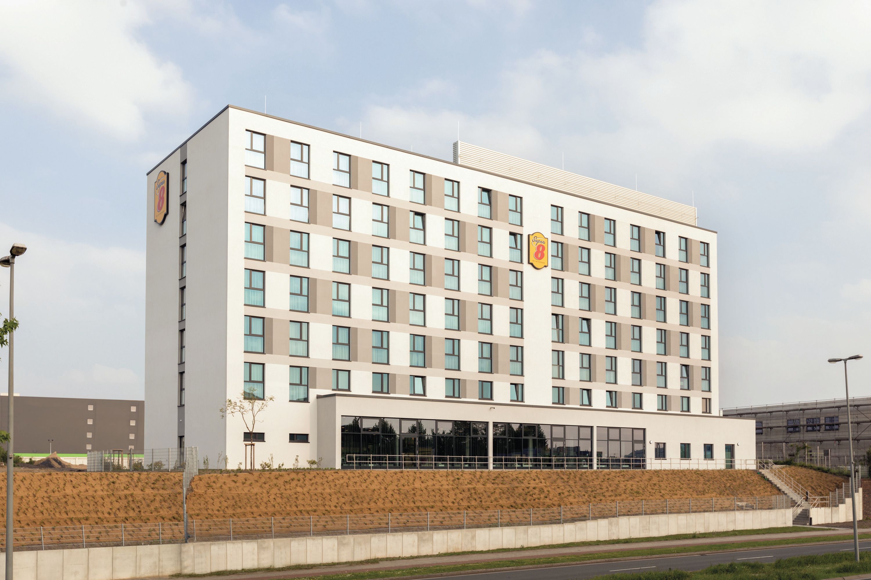 Ein mehrgeschossiges Hotel mit schlichter Fassade, großen Fenstern und einem gut sichtbaren Logo an der Seite.