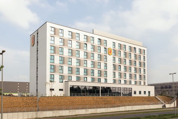 Un hôtel à plusieurs étages, doté d’une façade sobre, de grandes fenêtres et d’un logo bien visible sur le côté.